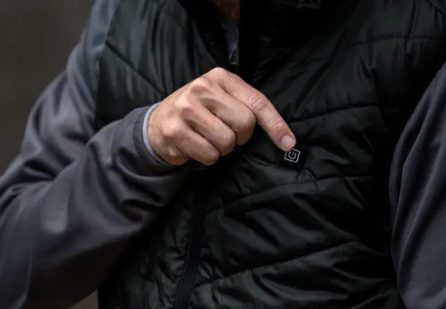 A hand pressing the vest's chest button