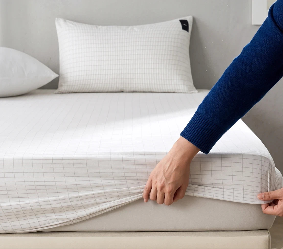 Hands fitting the Velin grounding sheet onto a mattress